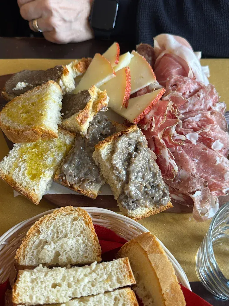 Tagliere di salumi con formaggi, cracker, pane e affettati su un tavolo di legno.