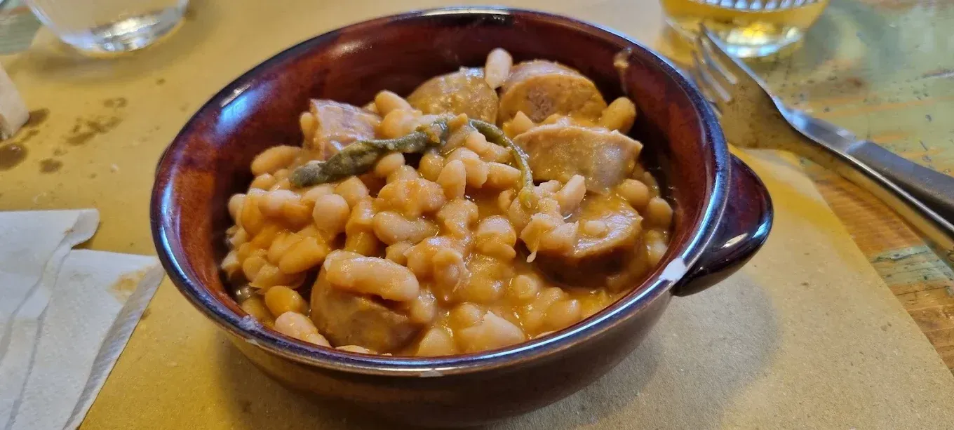 Una ciotola di stufato di fagioli su un tavolo con un cucchiaio nelle vicinanze.