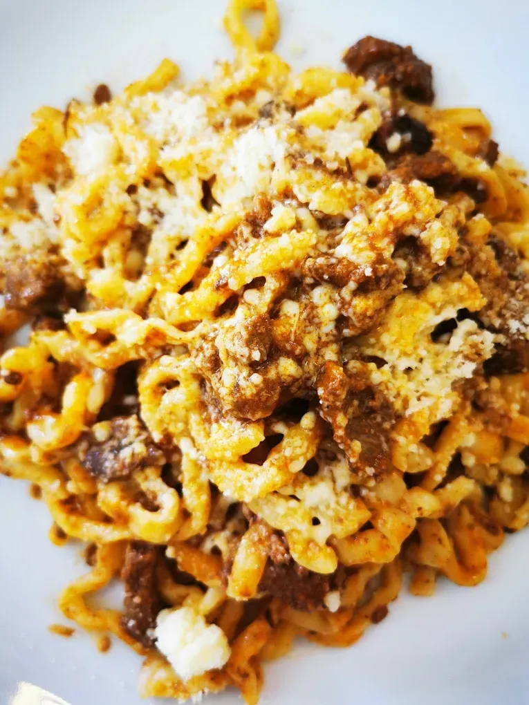 Piatto di spaghetti al ragù con formaggio grattugiato su un piatto bianco.