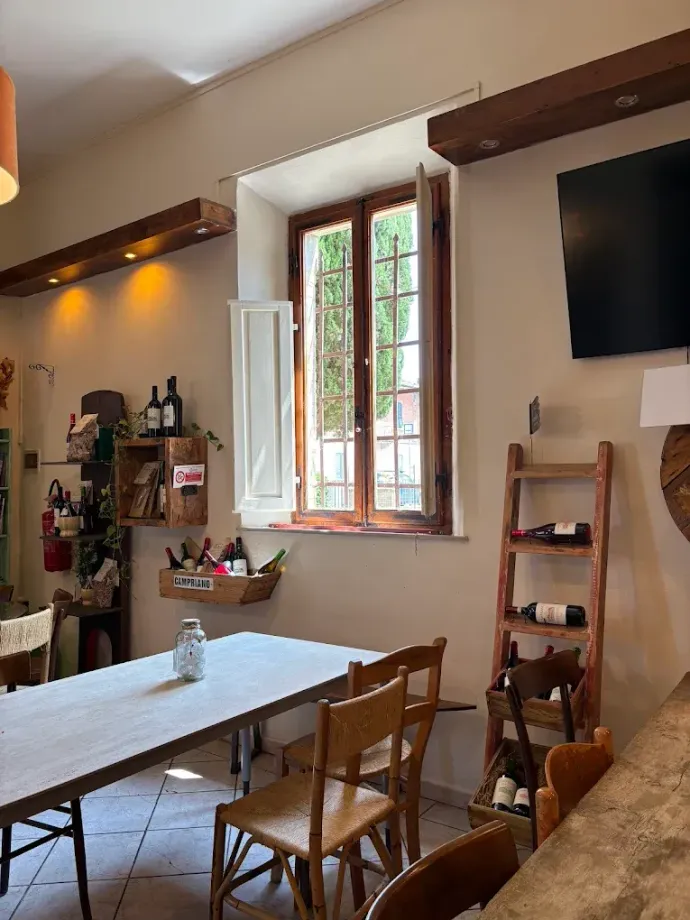 Accogliente interno di un caffè con tavoli in legno, lampade a sospensione e opere d'arte alle pareti vicino alle finestre.