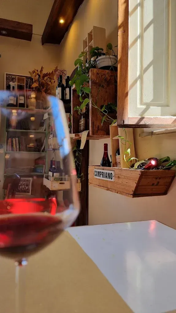 Interno rustico di un negozio di vino e olio d'oliva con tavoli e scaffali in legno e insegne 