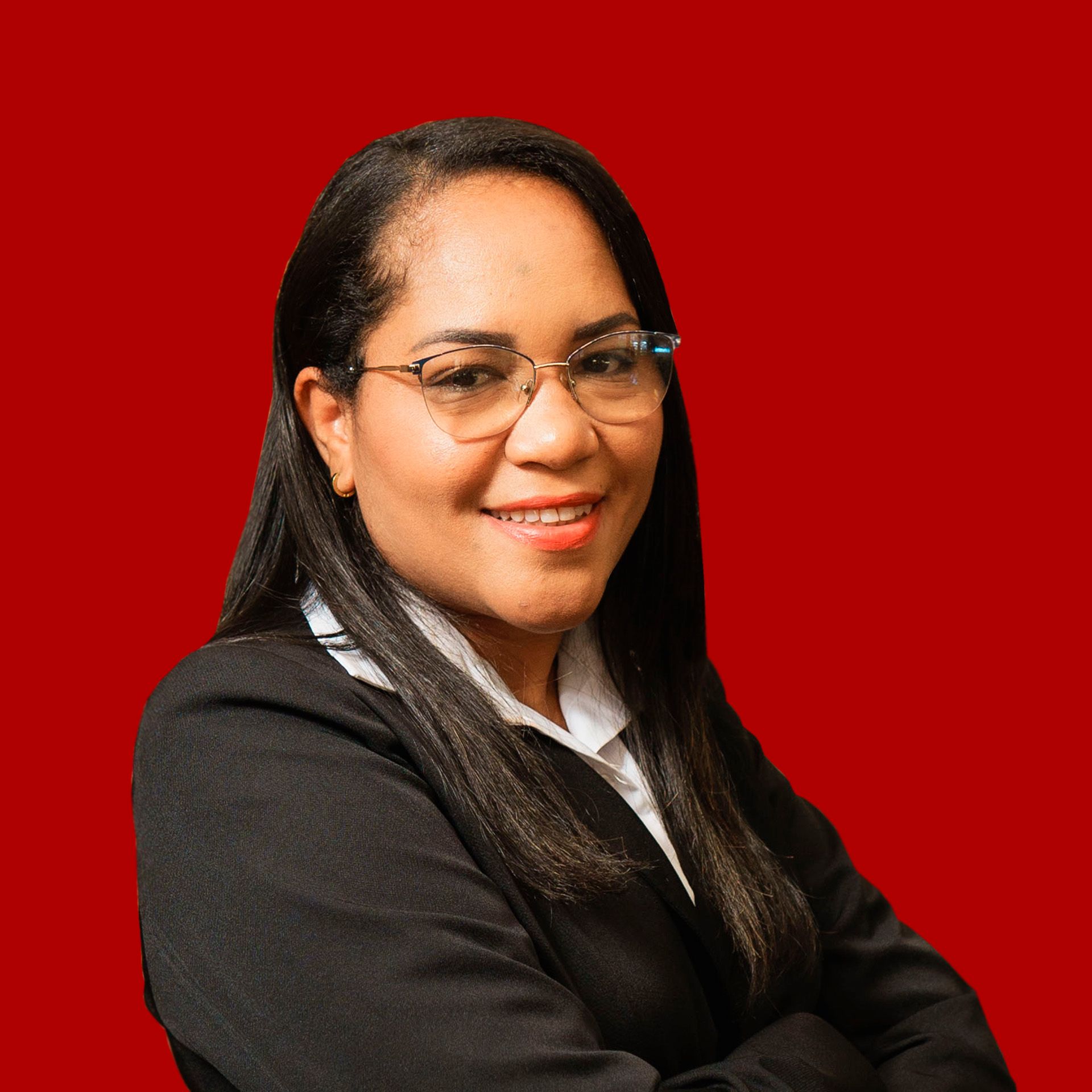 A woman wearing glasses and a black suit is smiling with her arms crossed.