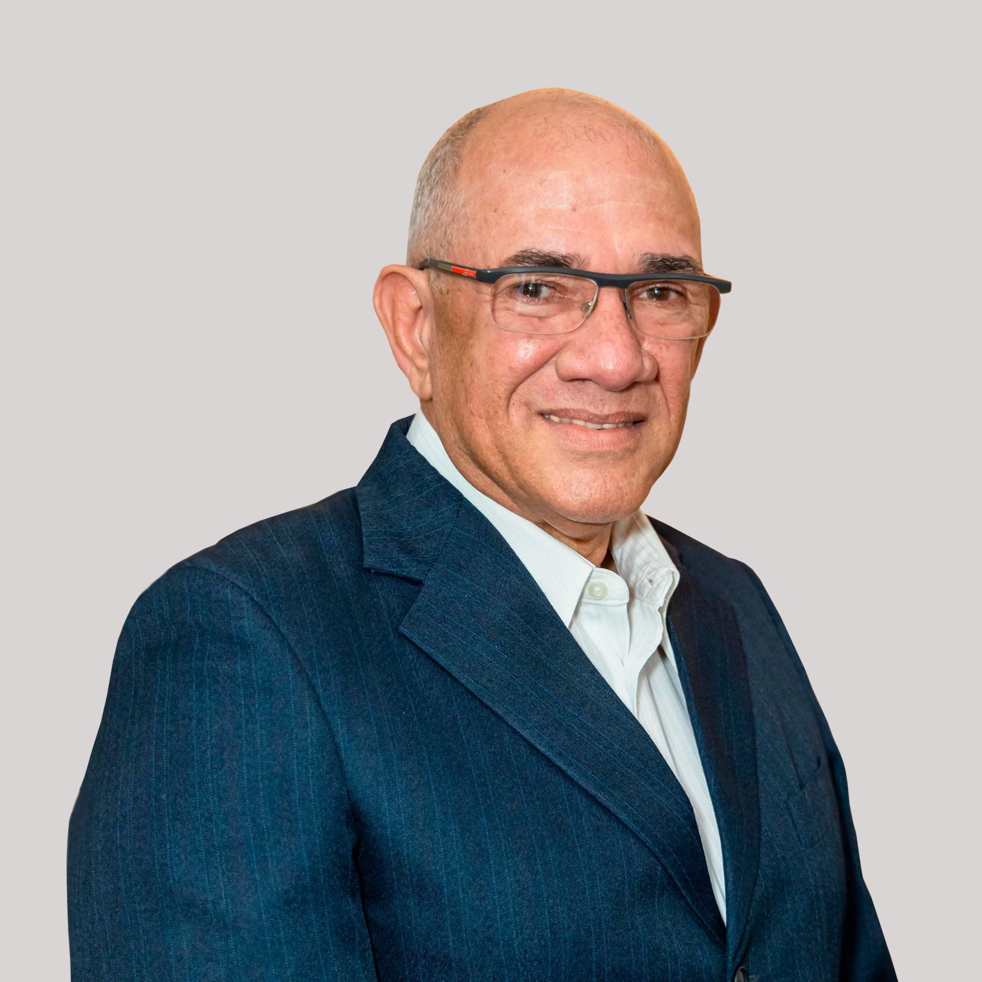 A man wearing glasses and a blue jacket is smiling for the camera.