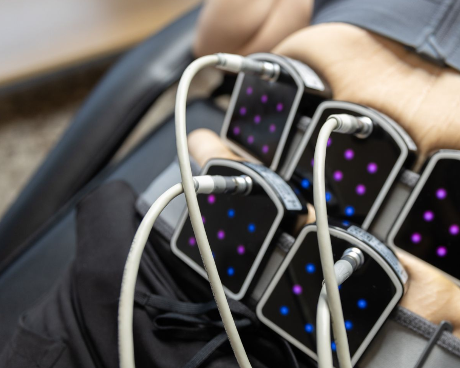 Person undergoing body contouring treatment with connected pads on abdomen.