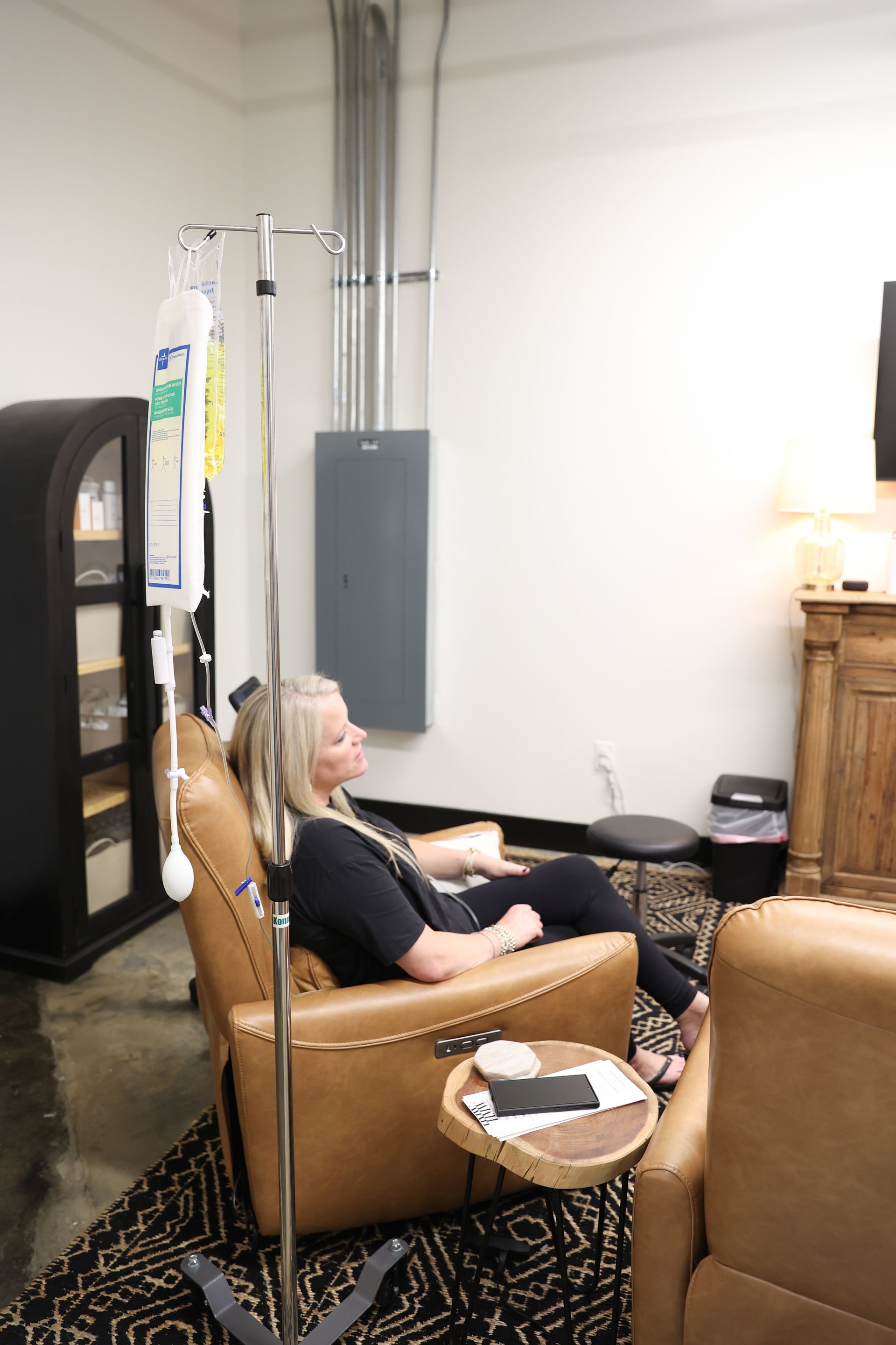 A woman is sitting in a chair with an iv in her arm.