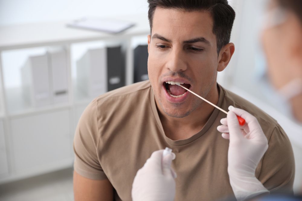 A man is getting a swab from his mouth.