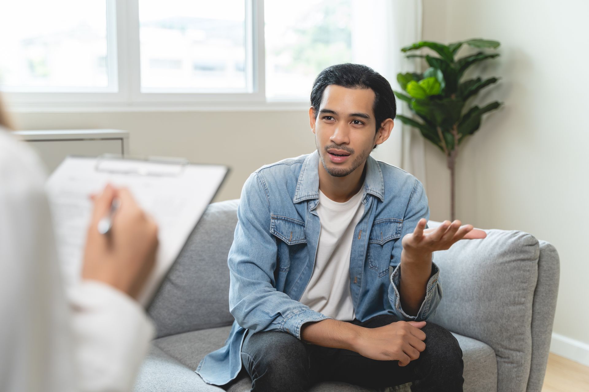 A man is sitting on a couch talking to a doctor.