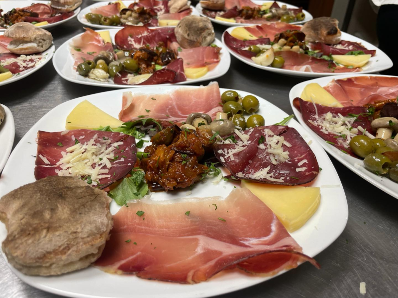 Piatti di salumi, formaggi, olive e pane disposti su un tavolo, pronti per un pasto.