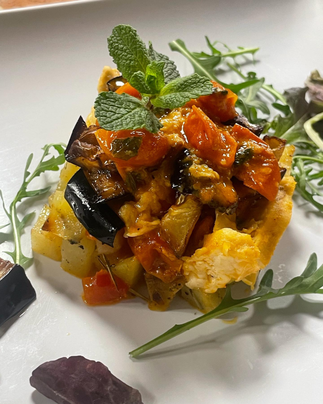 Antipasto gourmet di verdure condito con salsa e menta su un piatto bianco, guarnito con verdure