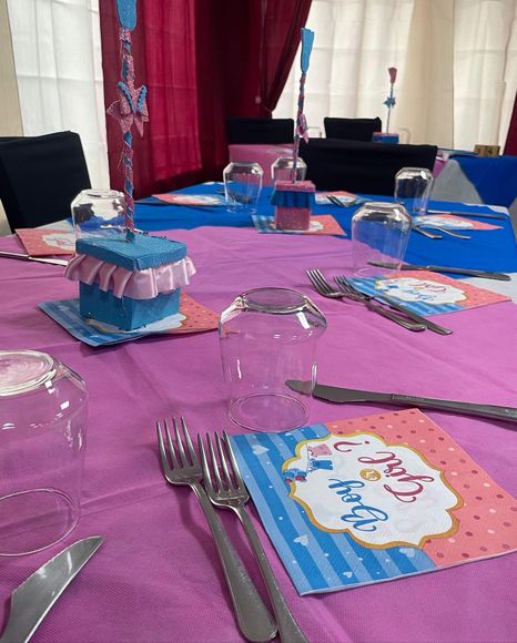 All'interno, apparecchiate la tavola con decorazioni per feste rosa e blu, bicchieri, posate e tovaglioli con disegni animati.