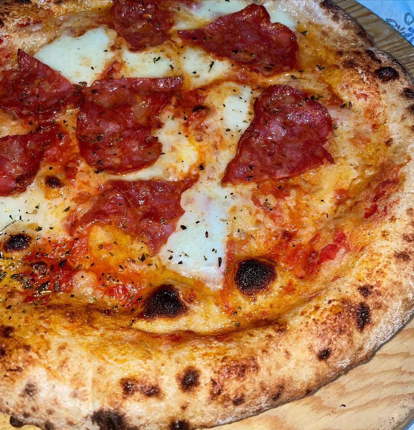 Primo piano di una pizza al salame piccante con formaggio fuso e crosta dorata.