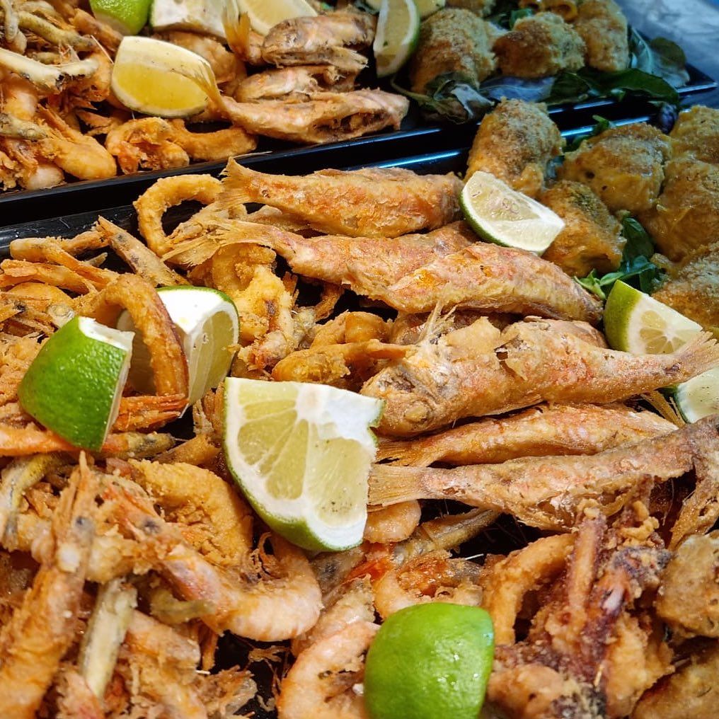 Vassoio di frutti di mare fritti con spicchi di limone e lime in una bancarella del mercato.