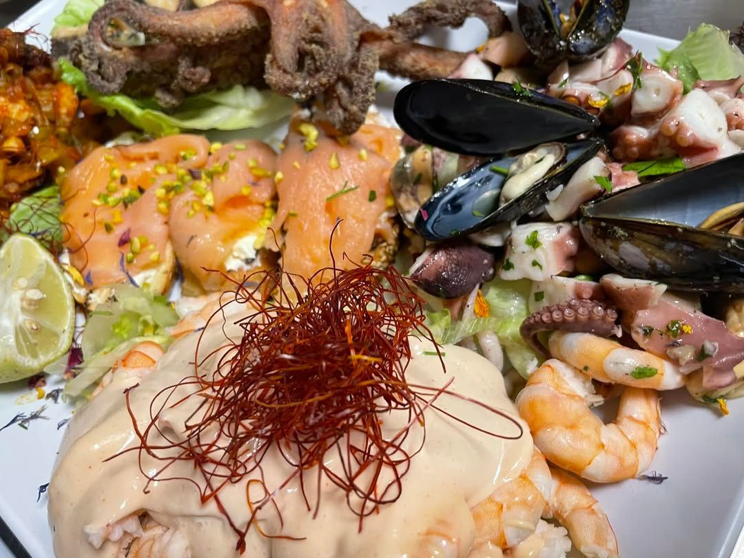 Piatto misto di frutti di mare con salmone, cozze, gamberi e capesante, guarnito con spezie.