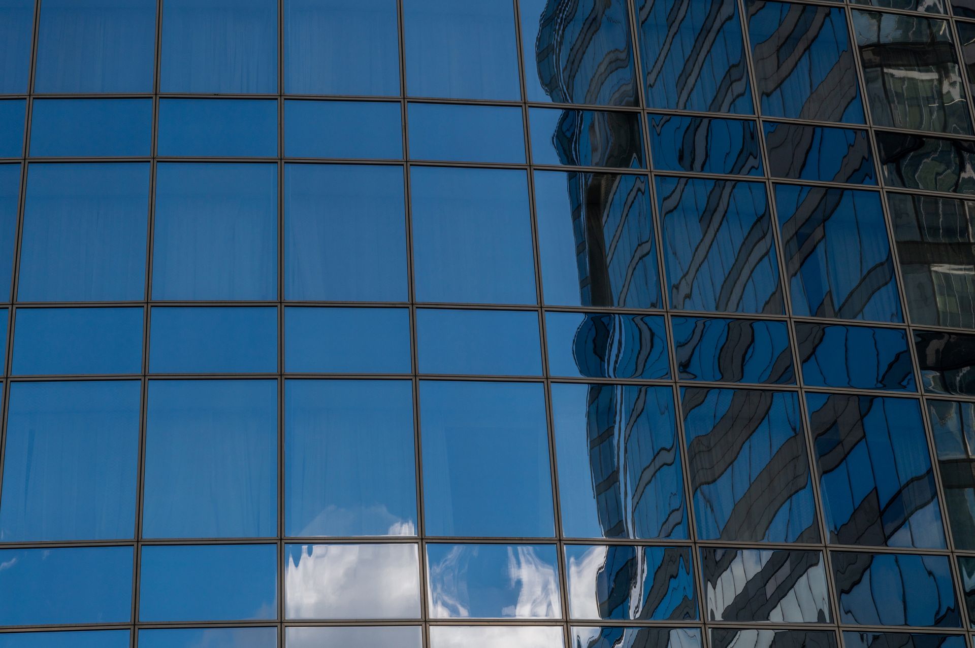 Le ciel se reflète dans les fenêtres d'un grand immeuble.