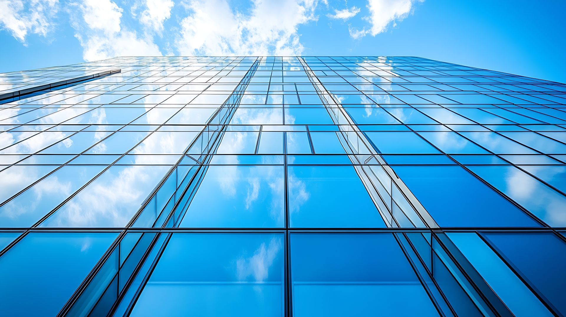 Regardant un grand bâtiment avec un ciel bleu et des nuages ​​​​reflétés dans les fenêtres.