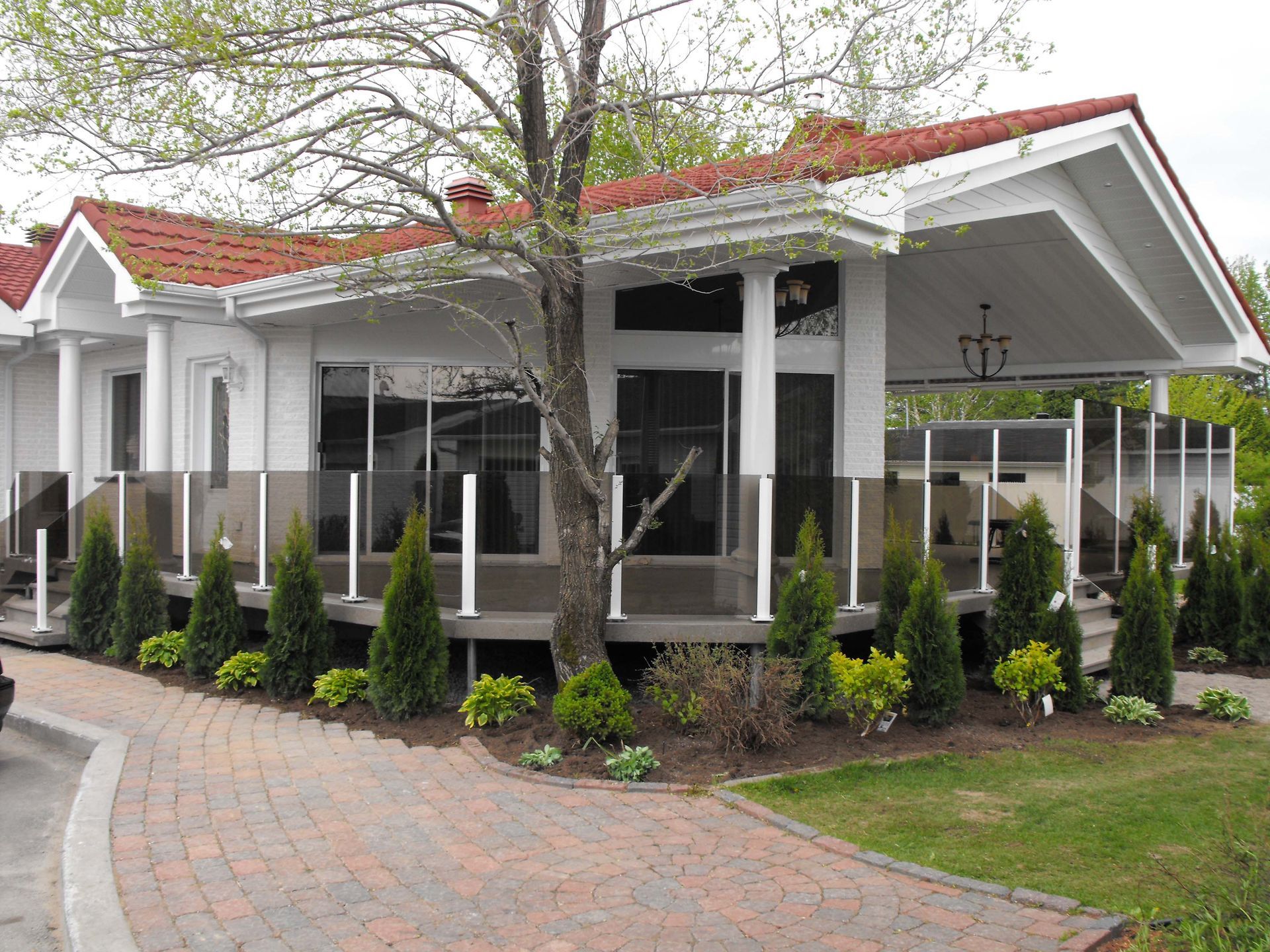 Une maison blanche avec un toit rouge et une allée en briques