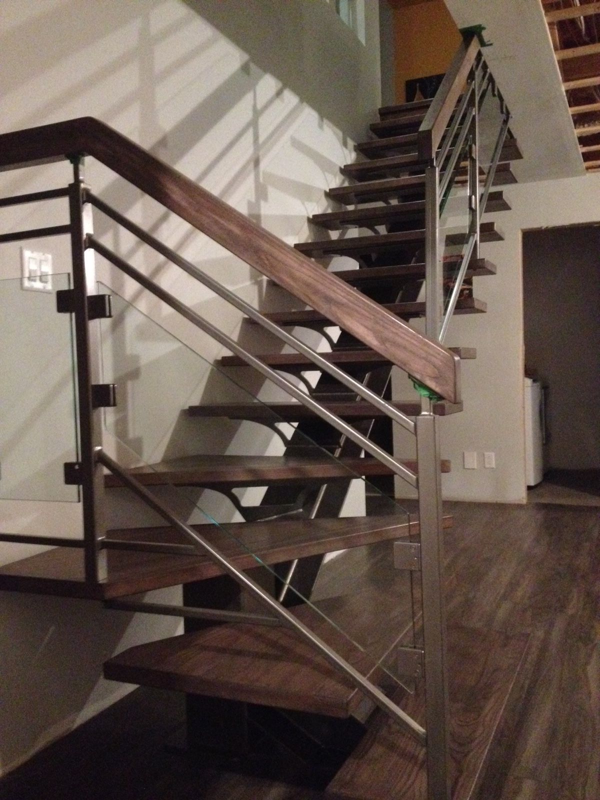 Un escalier en bois avec une rampe en acier inoxydable
