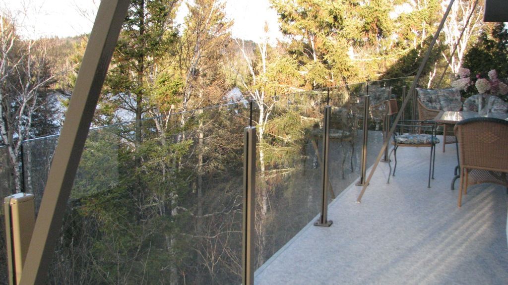 Un balcon avec une balustrade en verre donnant sur une forêt