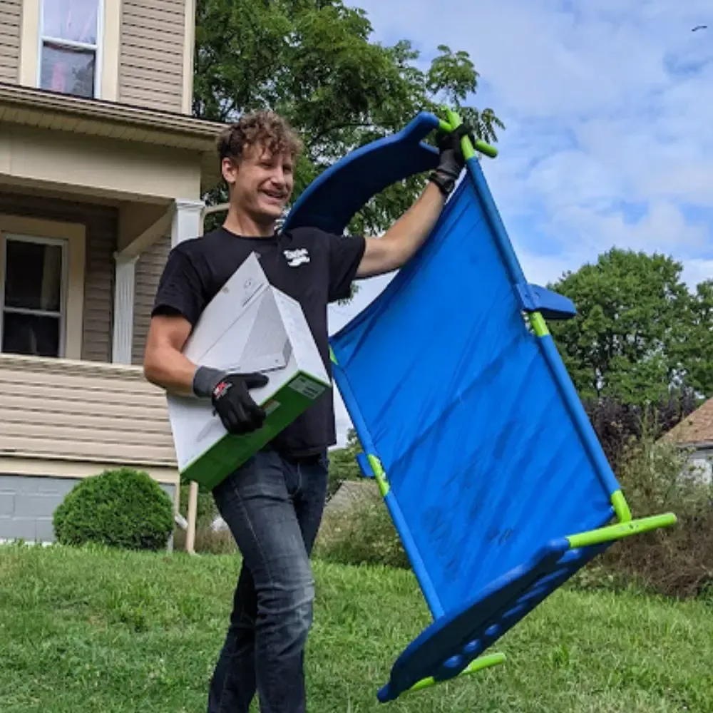 A man is carrying a blue table and a box