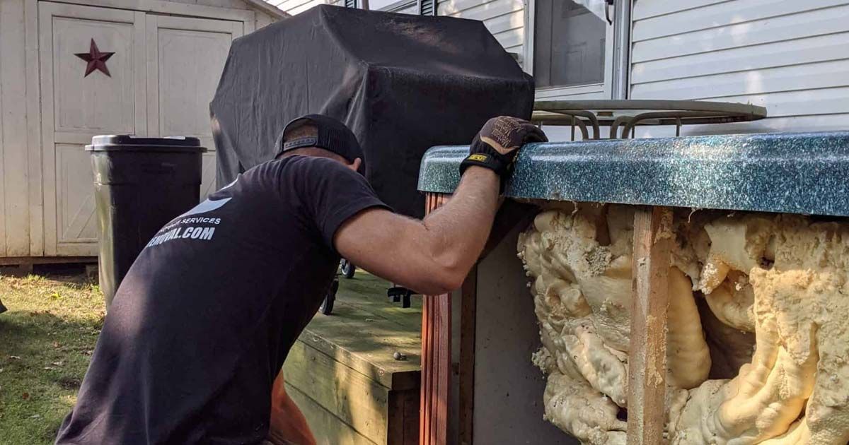 A man is working on a hot tub outside of a house.