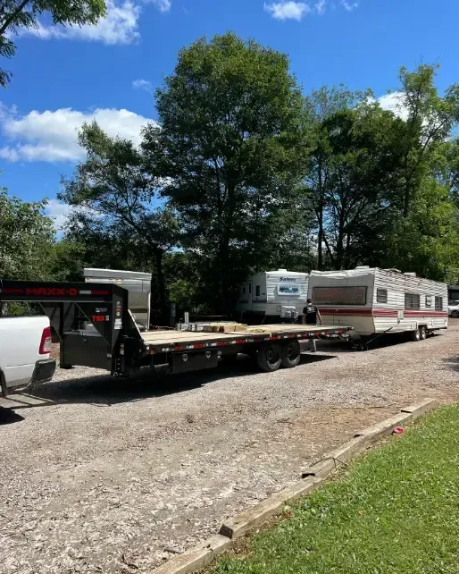 A truck is towing a trailer with a camper on it.