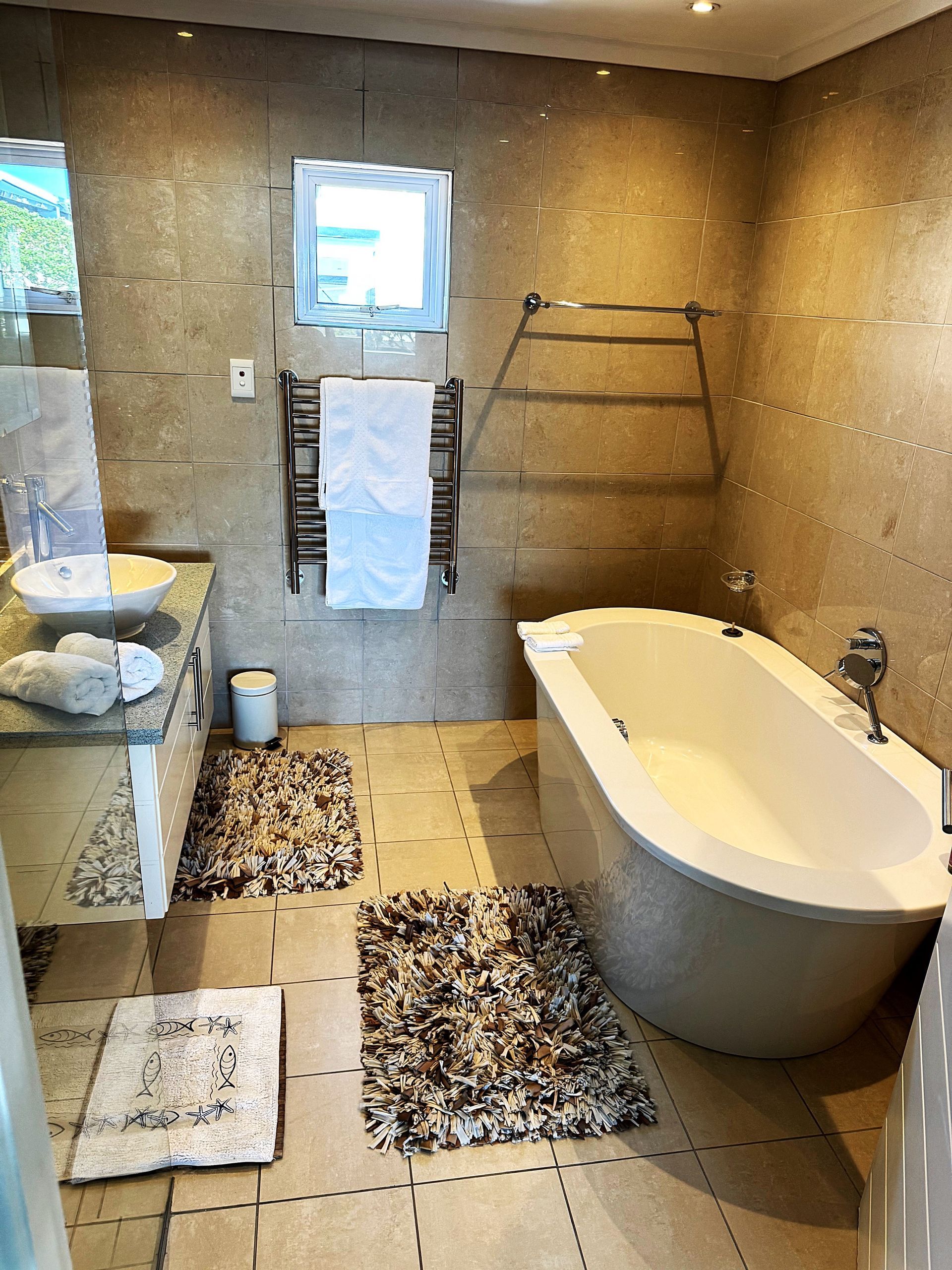 A bathroom with a bathtub , sink , and mirror.