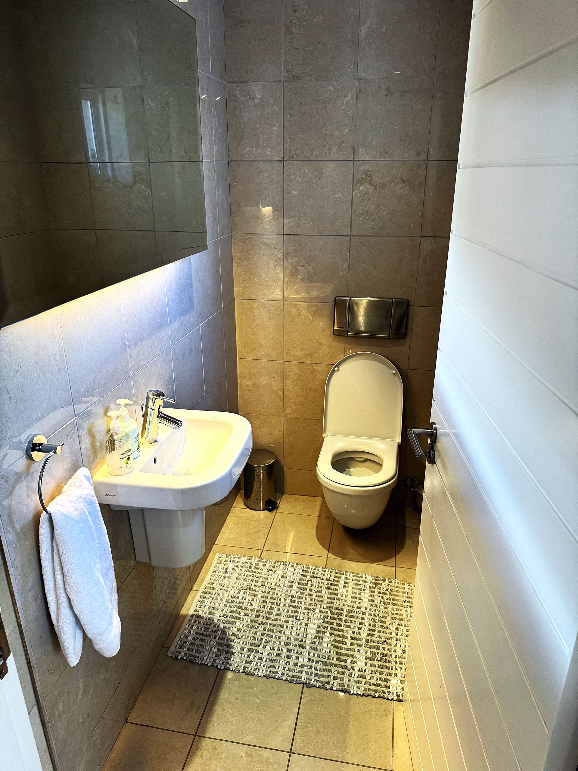 A bathroom with a toilet , sink and mirror