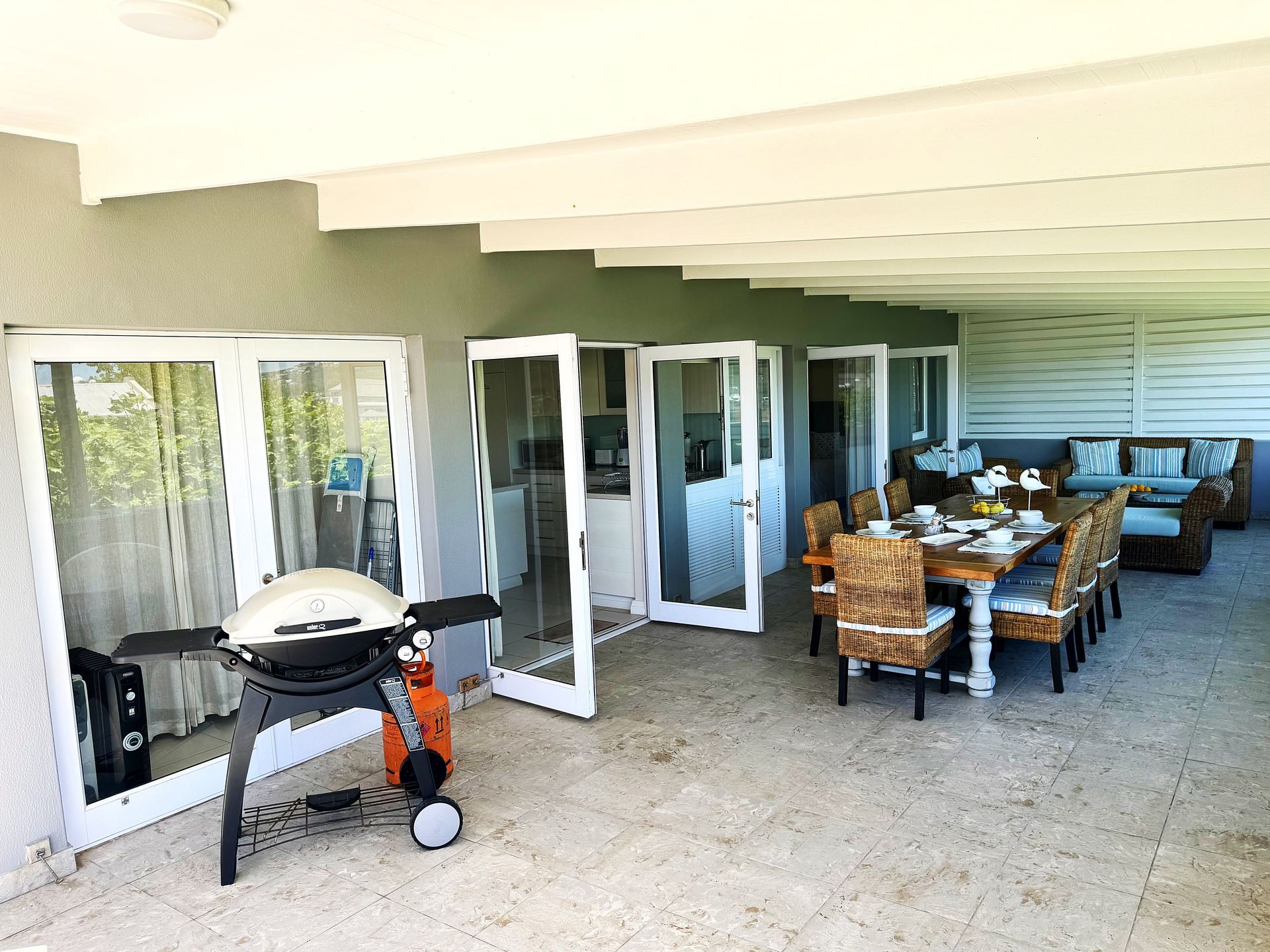 A large patio with a table and chairs and a grill