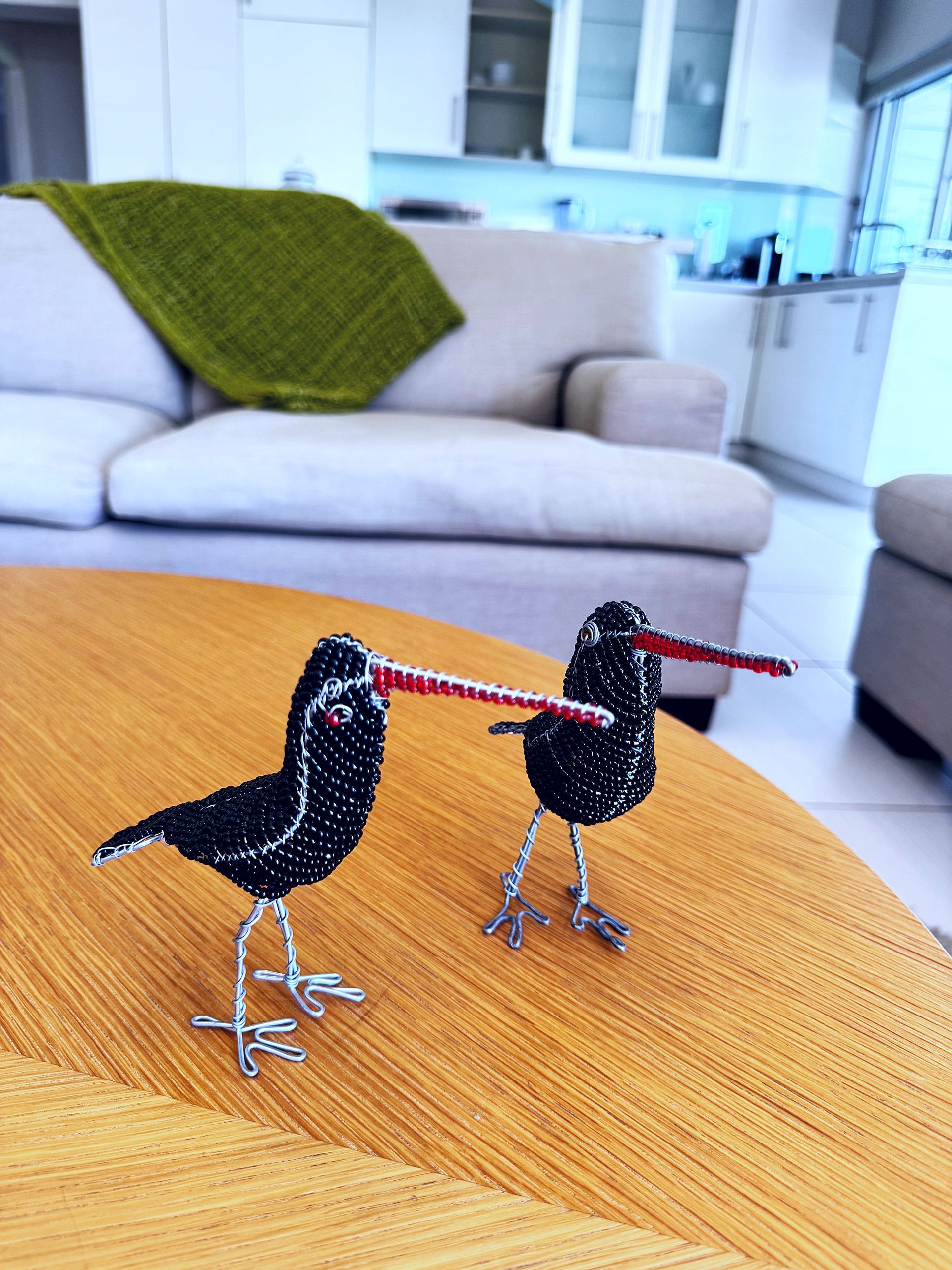 Two black birds are sitting on a table in front of a couch
