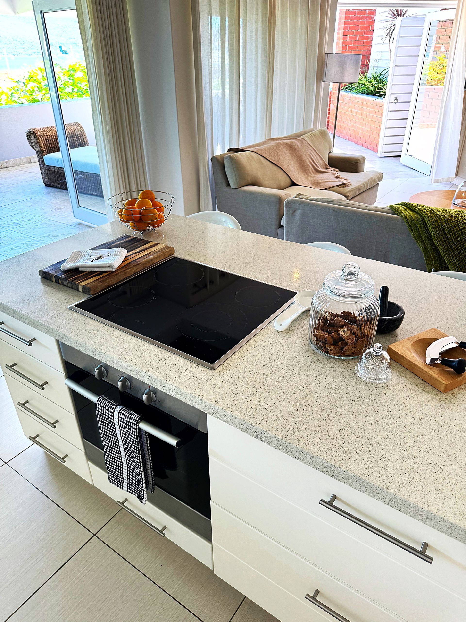A kitchen with a stove top oven and a living room in the background.