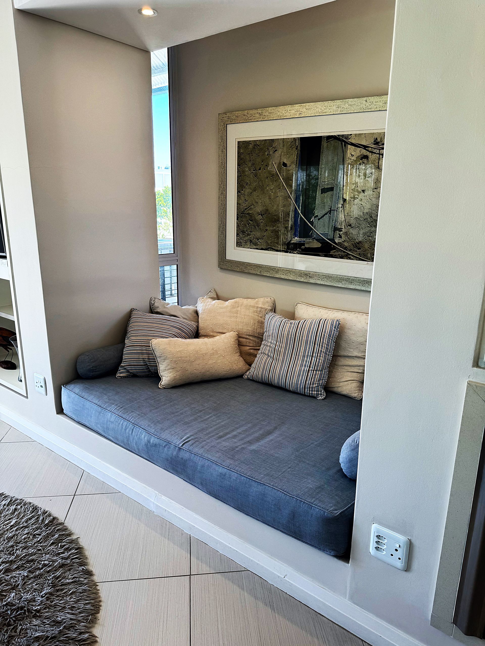 A couch with pillows and a picture on the wall in a living room.