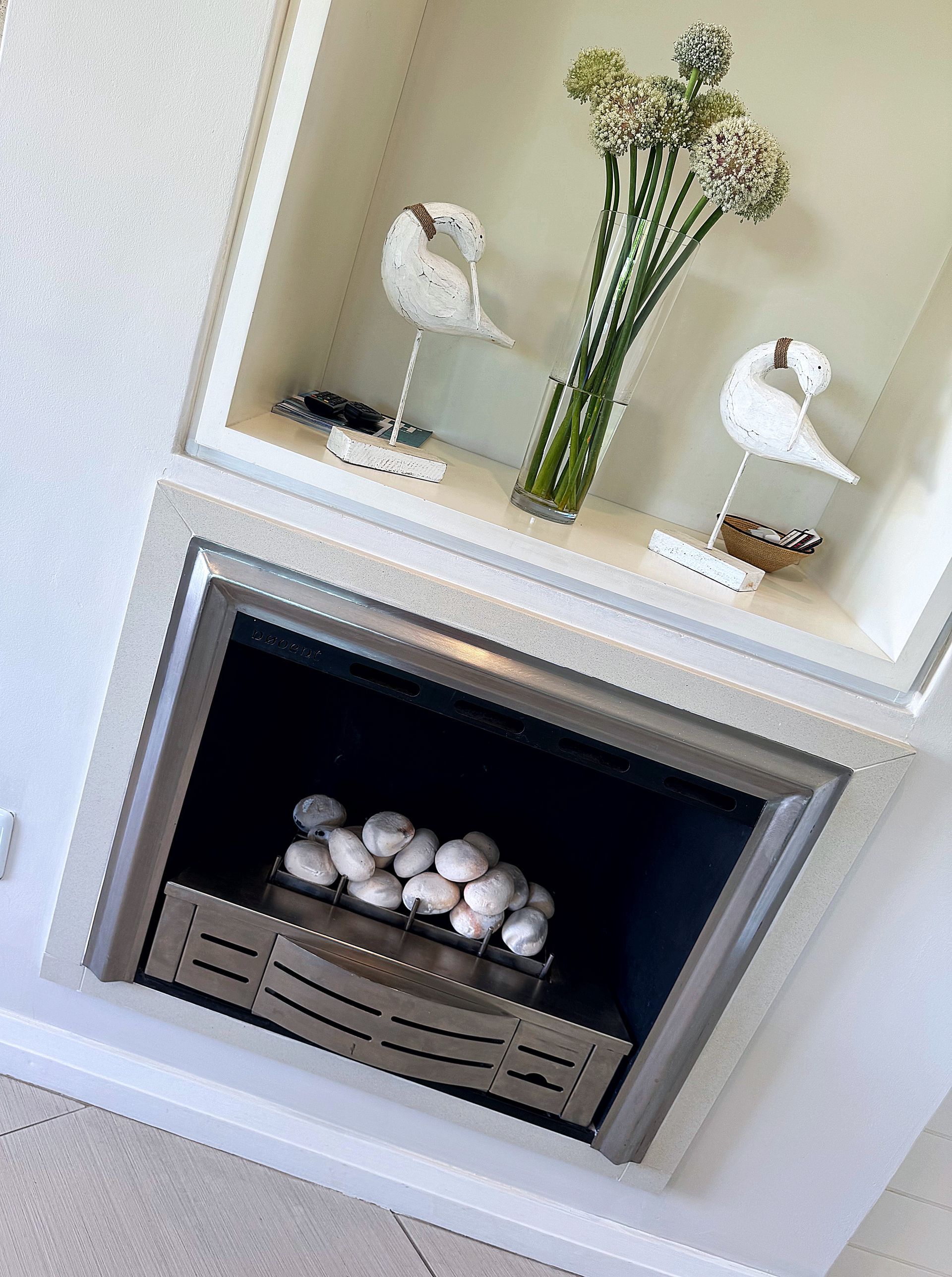 A fireplace with a vase of flowers on top of it.