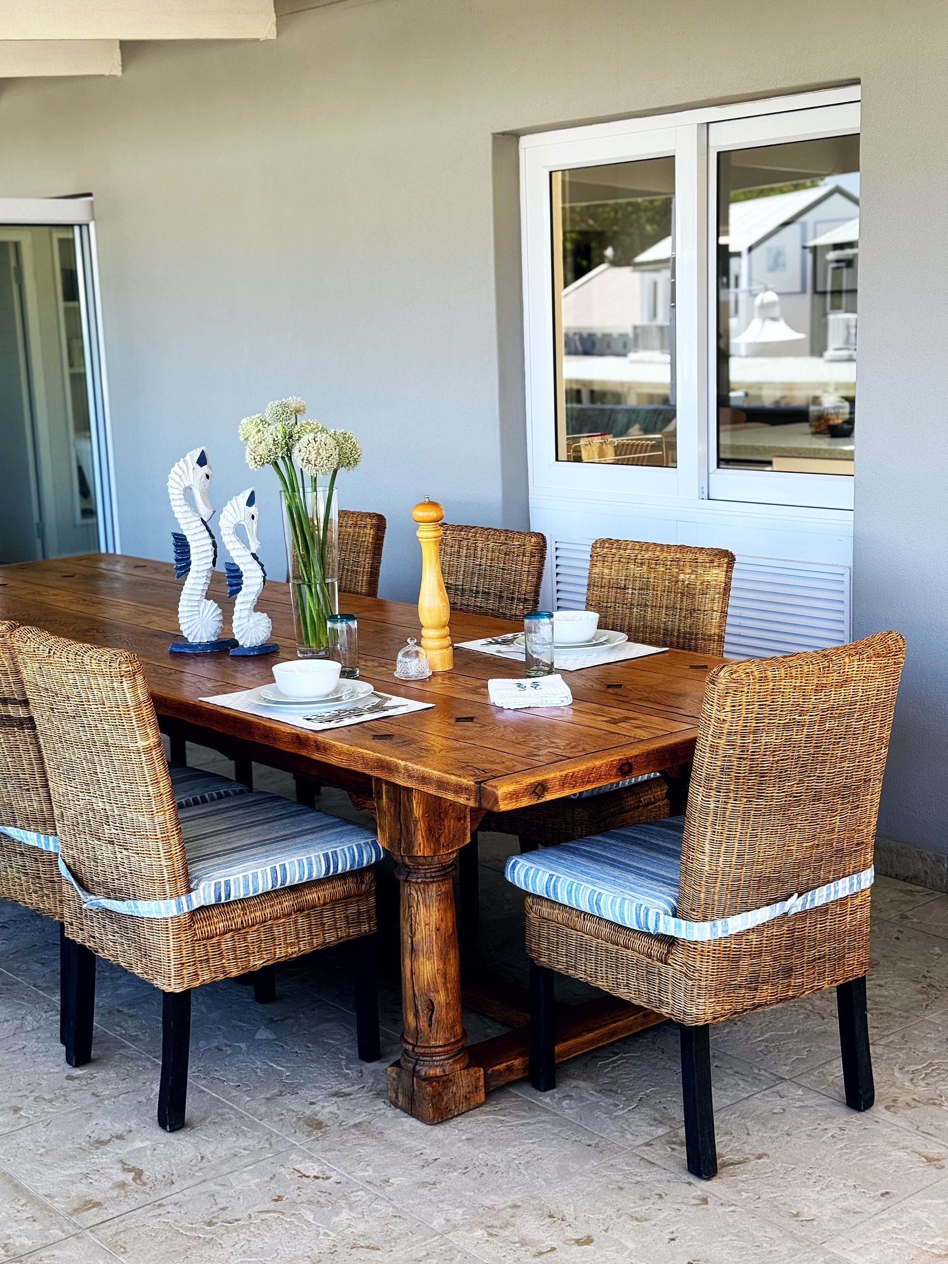 A wooden table with wicker chairs and a vase of flowers on it