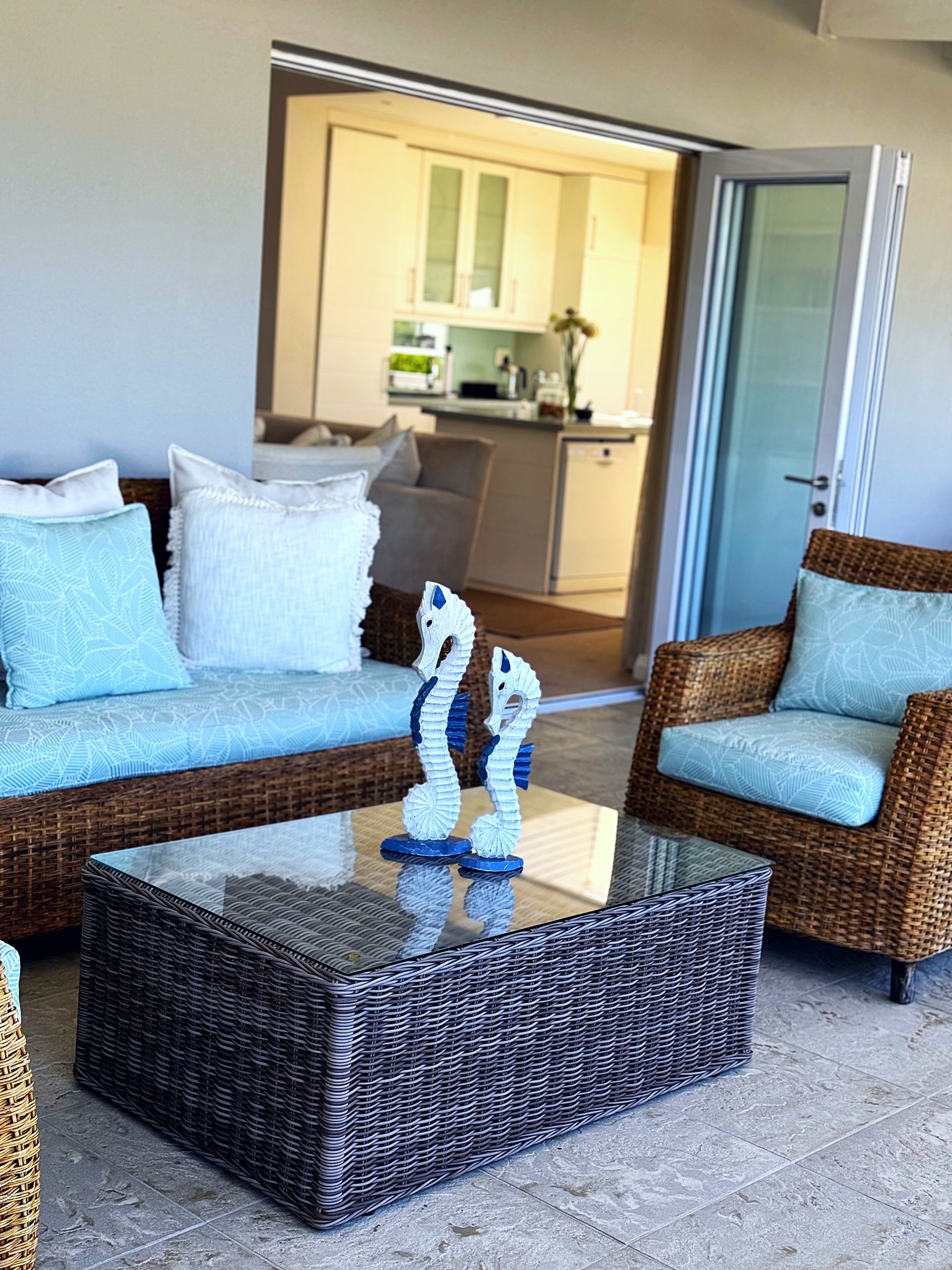 A living room with wicker furniture and a glass coffee table