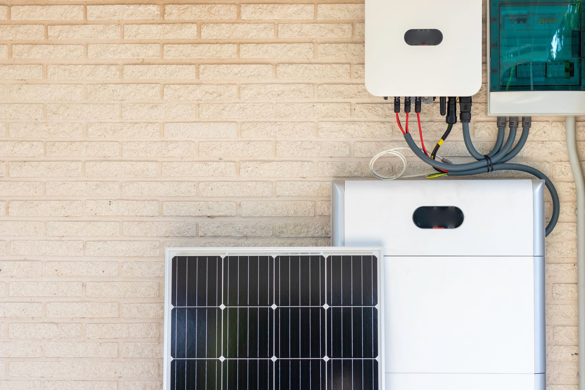 Front view of photovoltaic panel and battery installation against a beige wall.