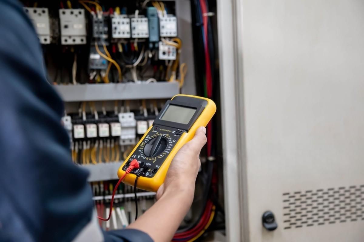 a person is holding a digital multimeter with a red wire attached to it