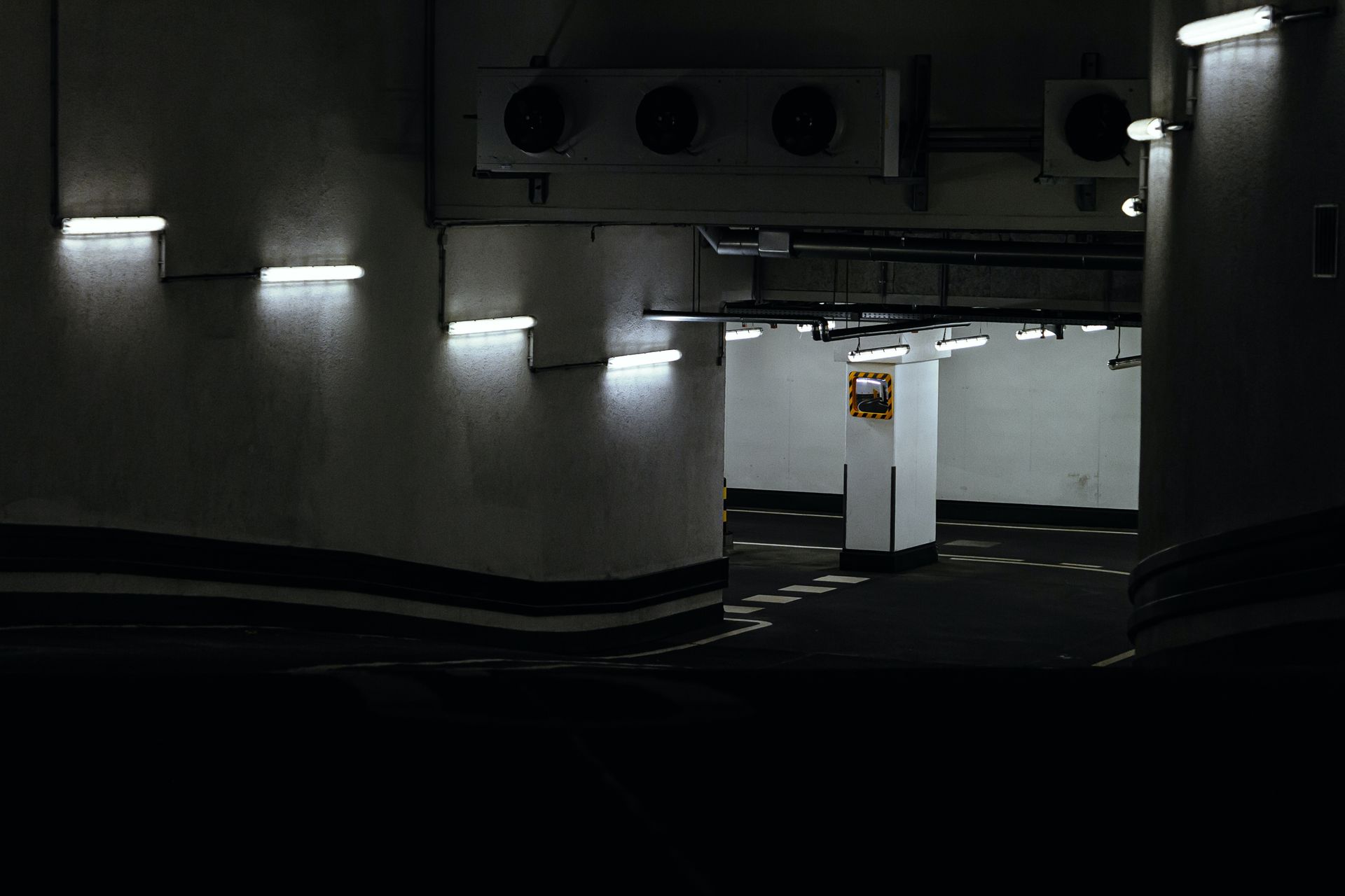 Dimly lit parking lot at night with a multitude of fluorescent lights illuminating the area.