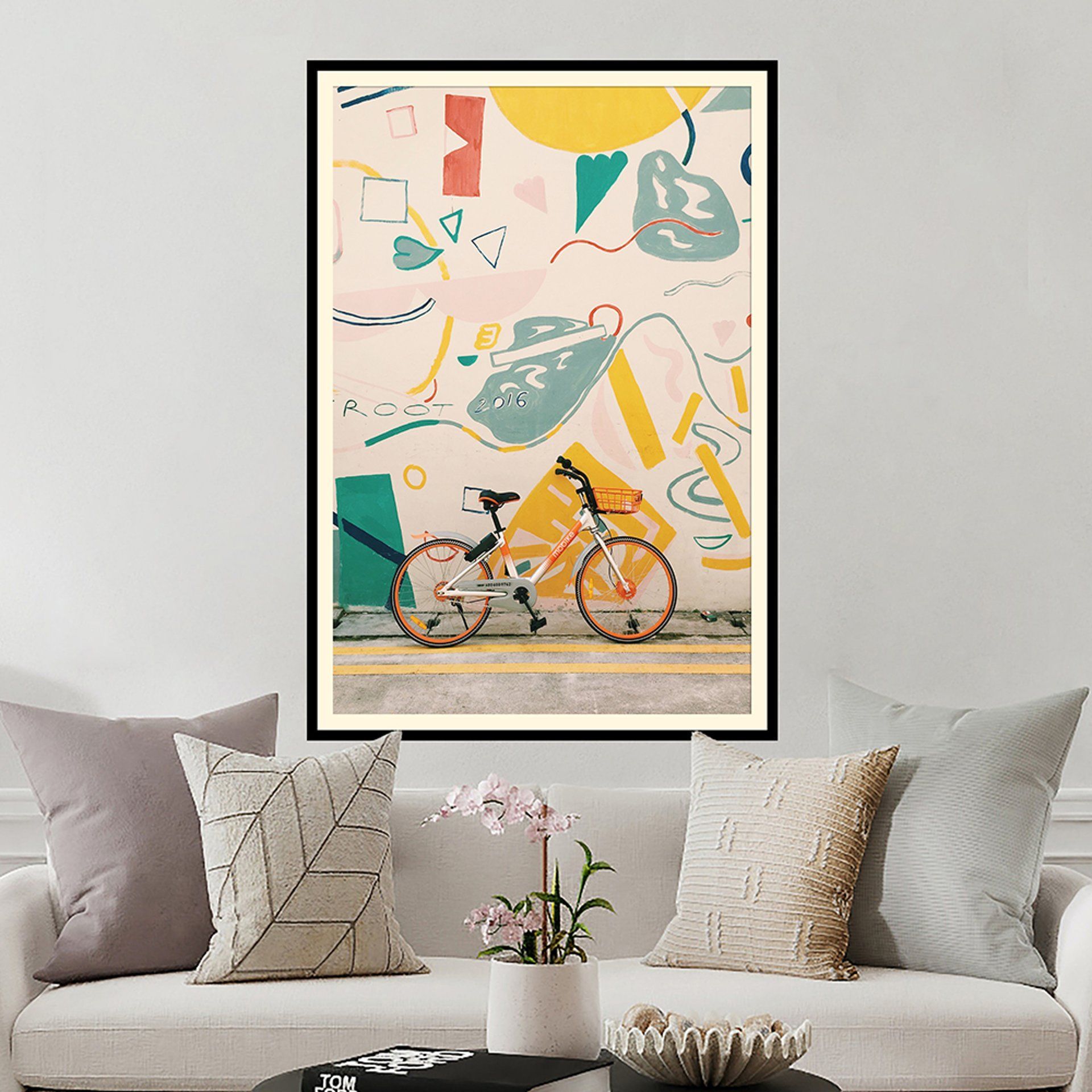 A painting of a bicycle is hanging on a wall above a couch