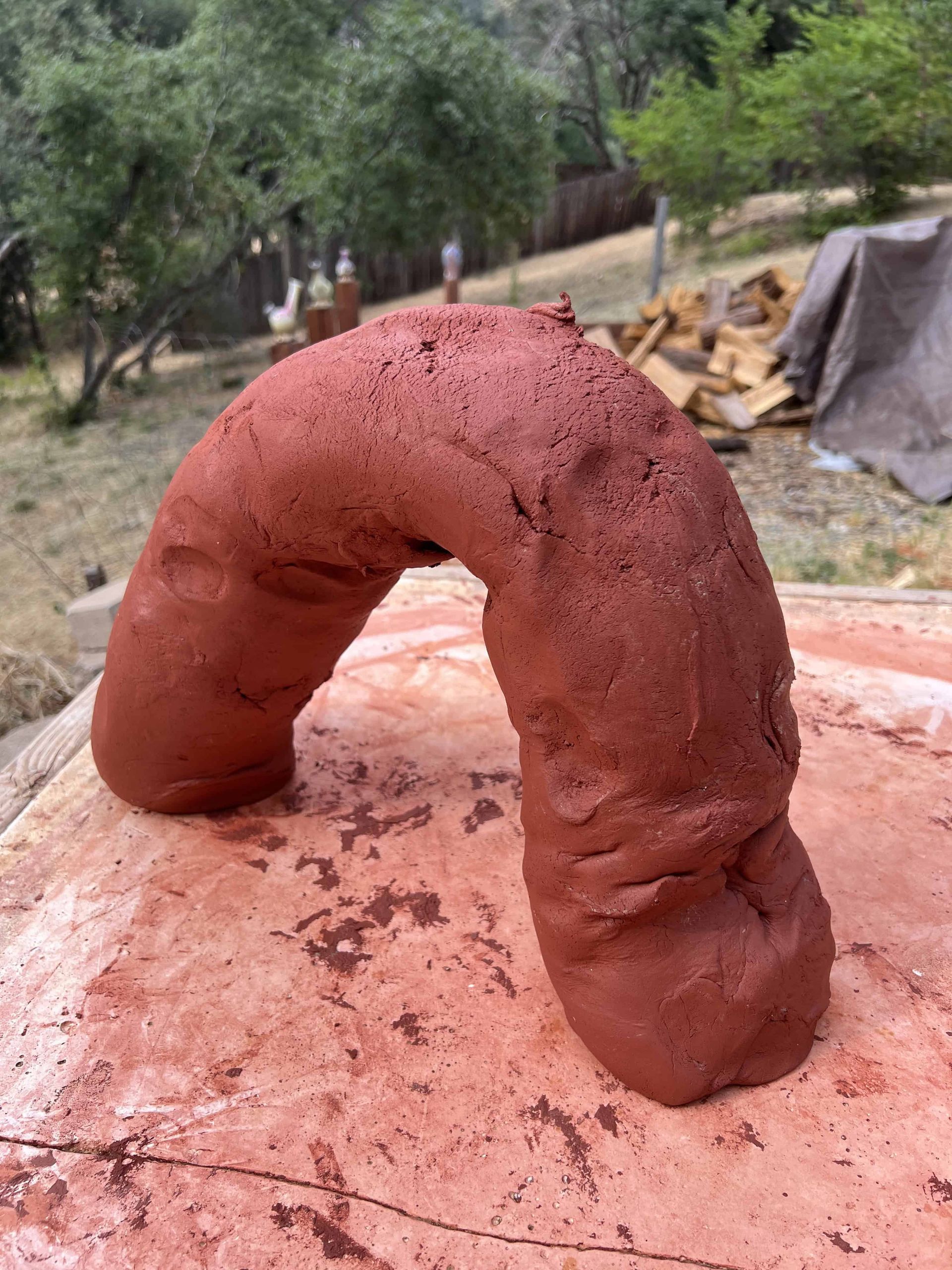 Terracotta clay shaped into an arch, standing on a flat table