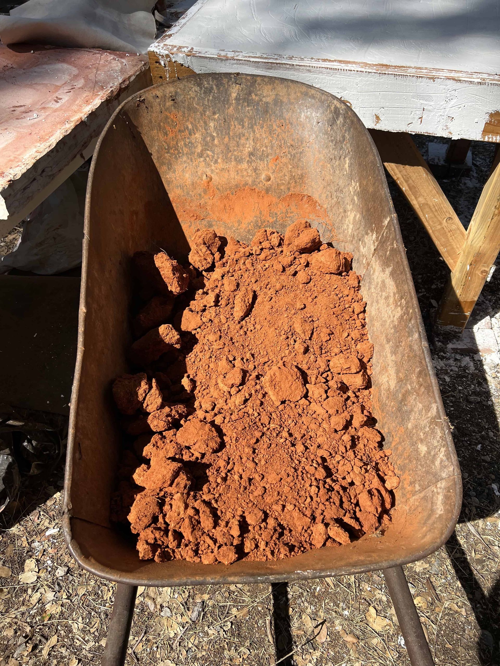 Red earth ready to be crushed in the old wheelbarrow 
