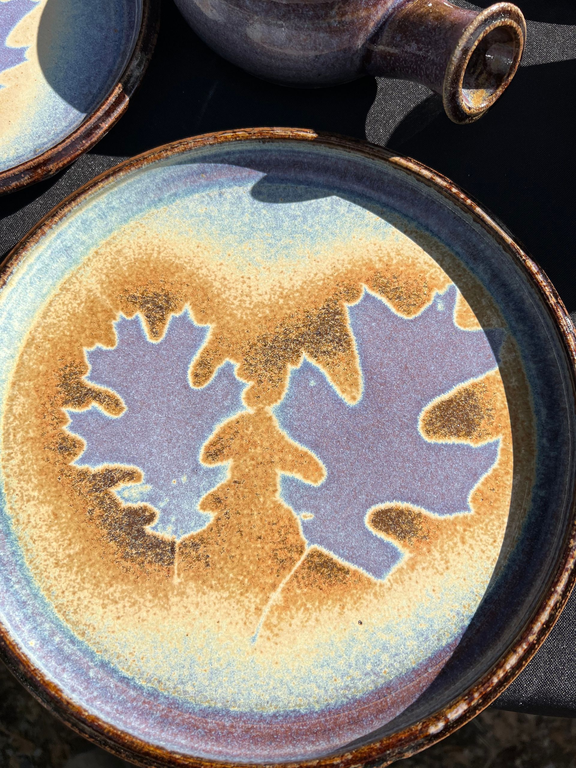 Blue and yellow ceramic plate with two purple oak leaf silhouettes in the center.