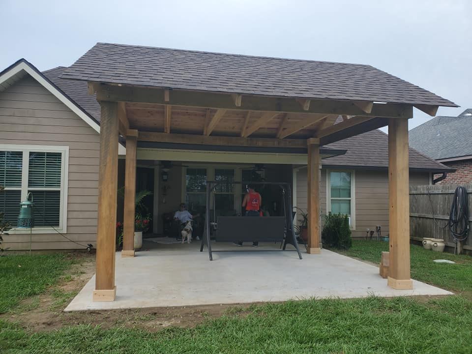 Patio with wooden pergola and swing set. People seated inside, overlooking a grassy yard.