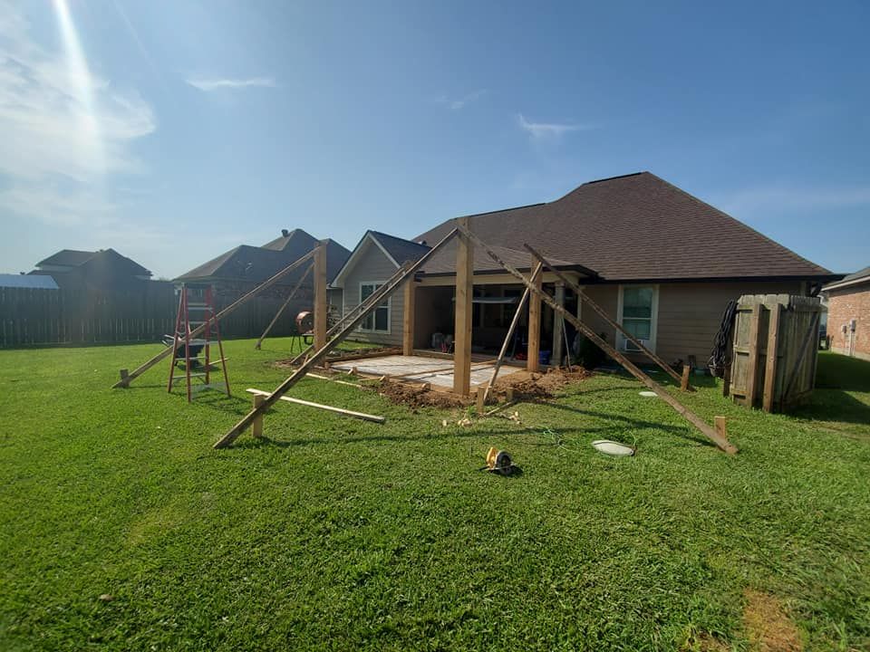 Construction of a patio cover in a backyard, using wooden posts and supports.