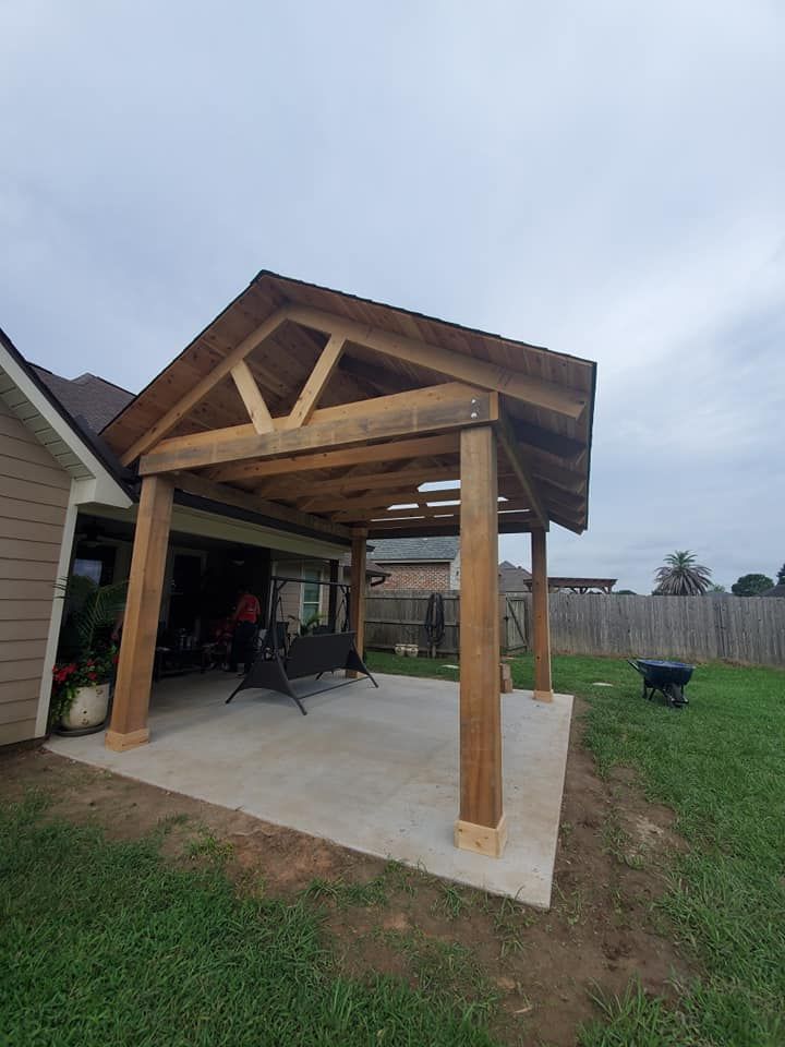 Wooden patio cover attached to a house with concrete flooring, swing, and grass.