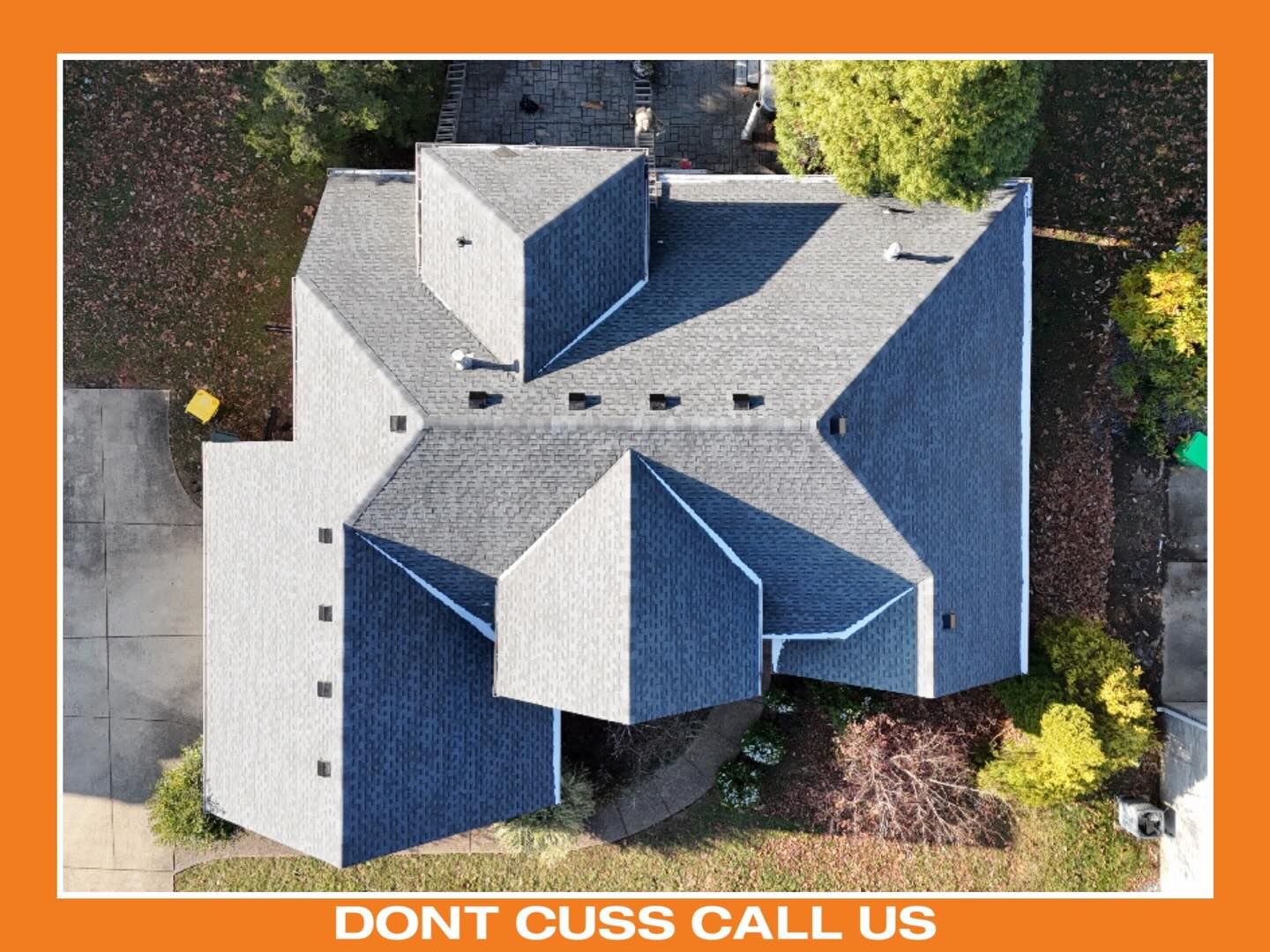 An aerial view of a gray-shingled residential roof with multiple peaks and a driveway
