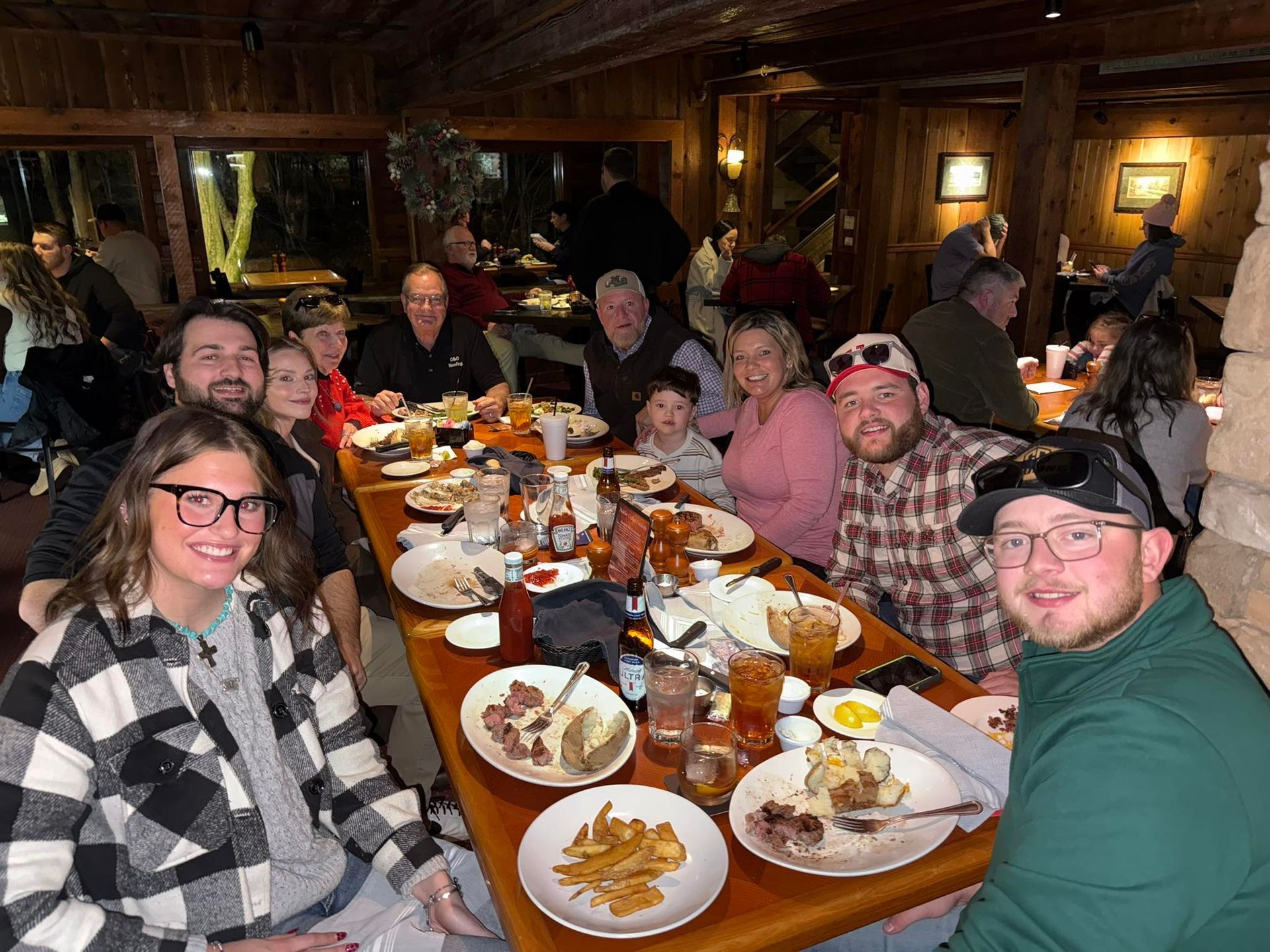 A group of people dining together at a long wooden table inside a dimly lit, rustic restaurant.