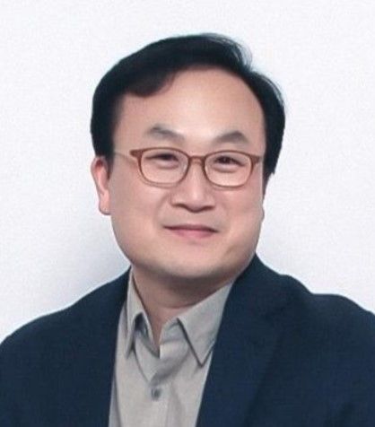 a man wearing glasses and a blue jacket smiles for the camera