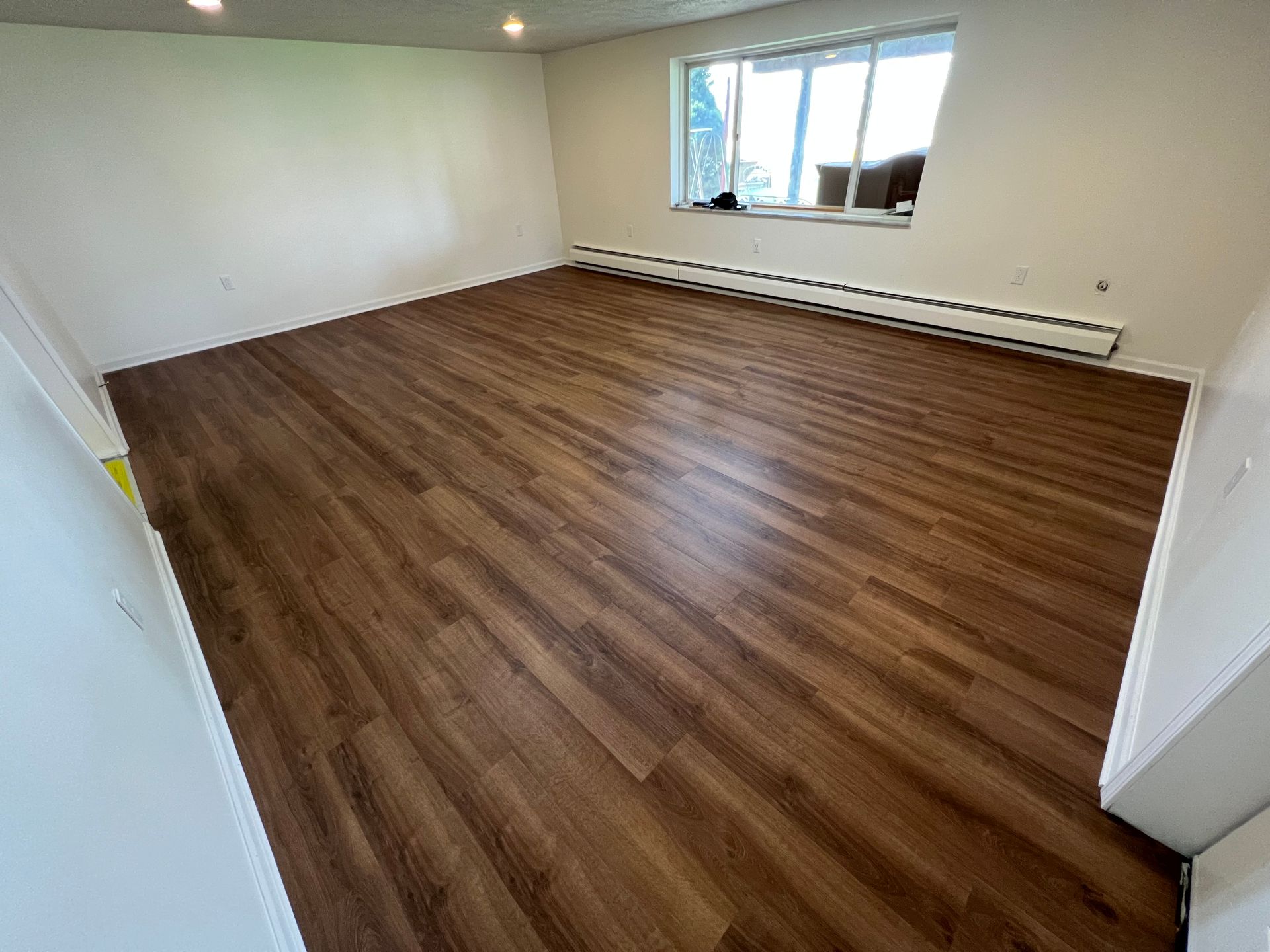 A living room with a wooden floor and a window.