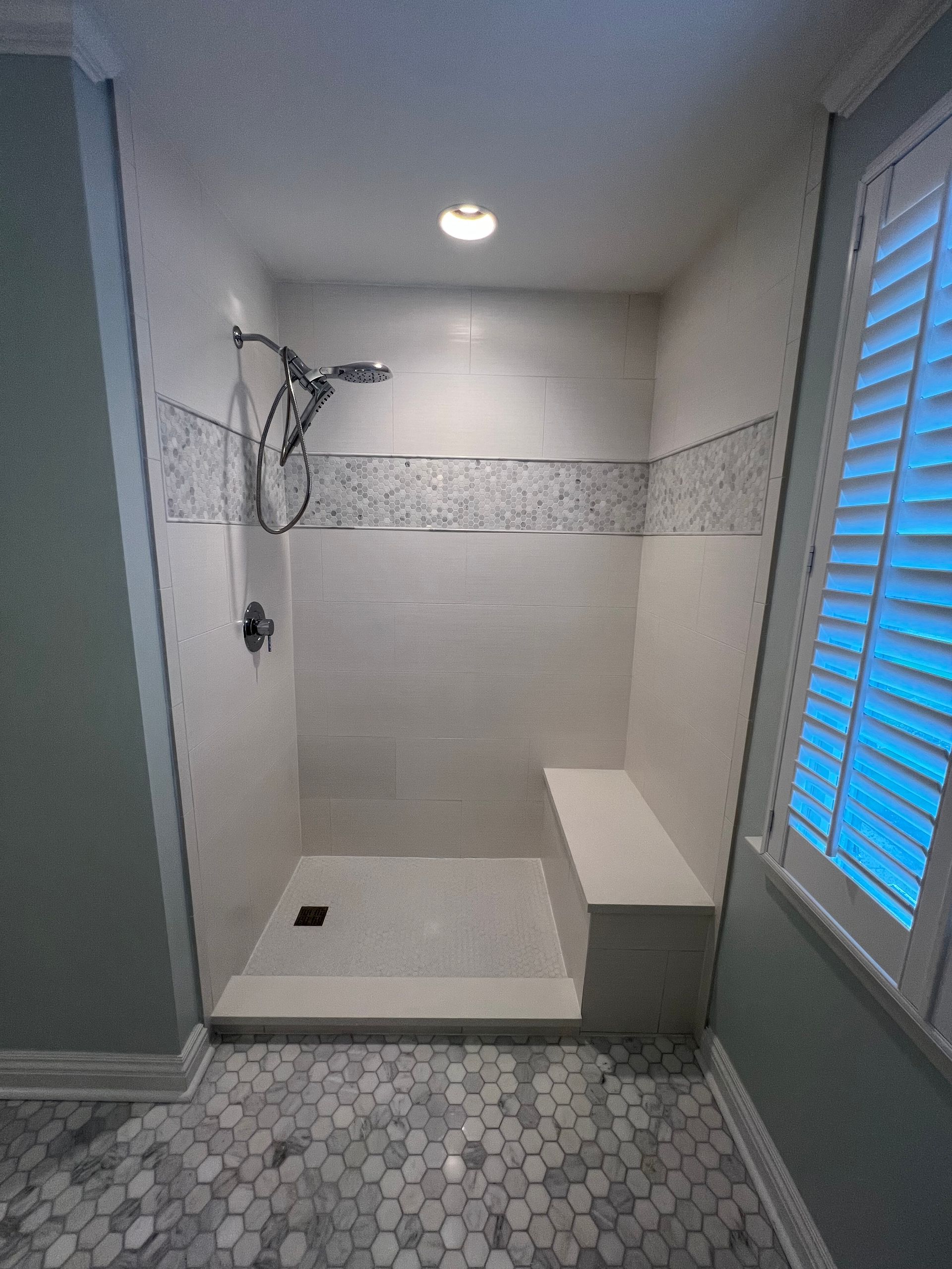 A bathroom with a walk in shower and a black and white tile floor.