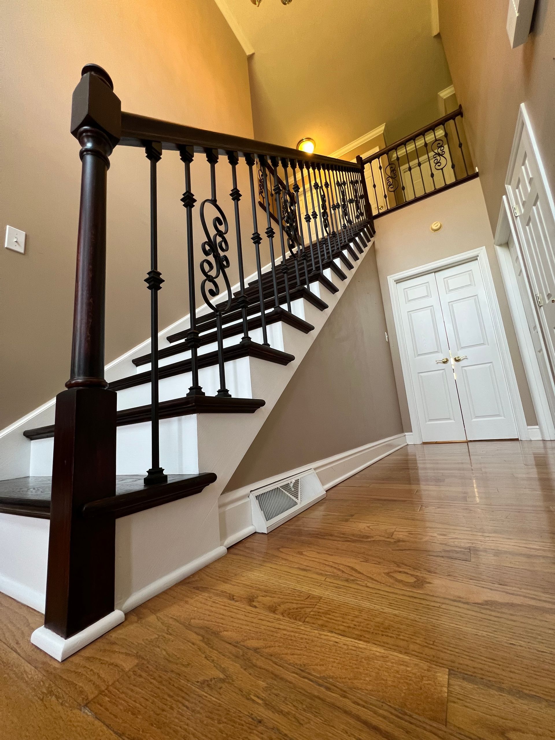 A wooden staircase with a wrought iron railing